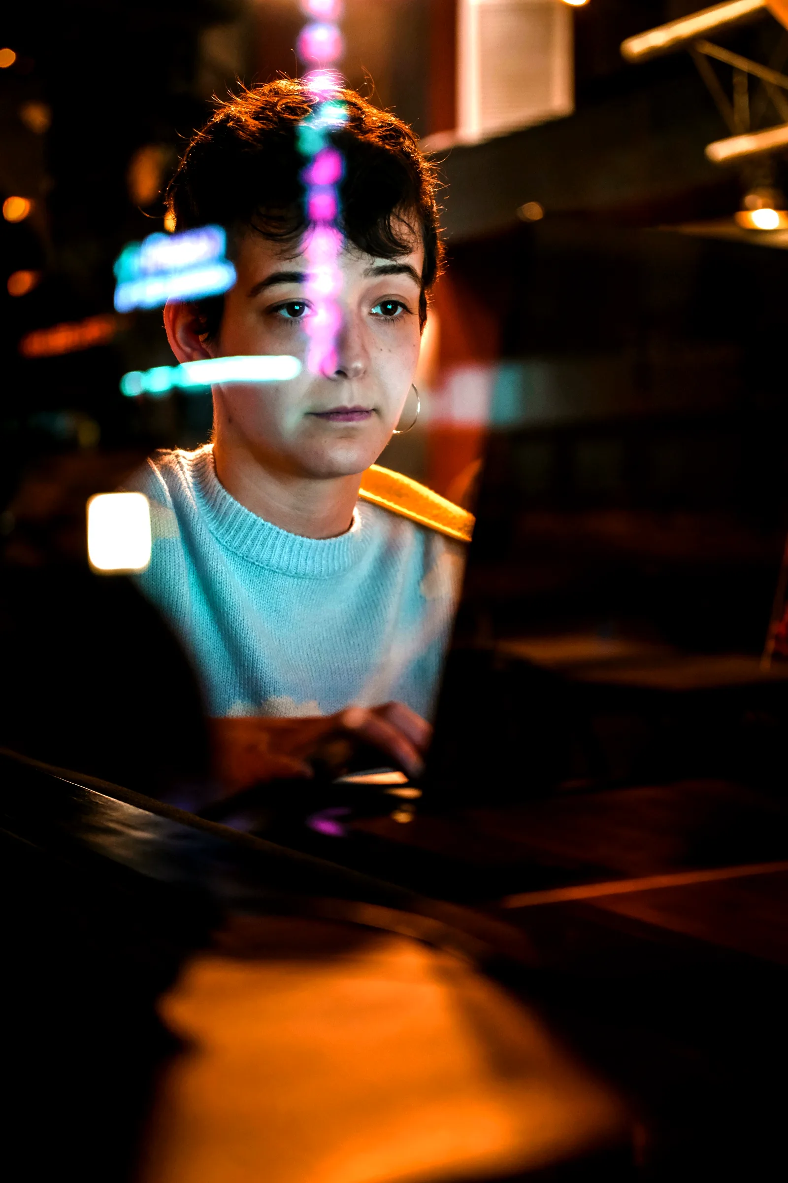 A person concentrating on a screen through glass with warm and cyan reflections
