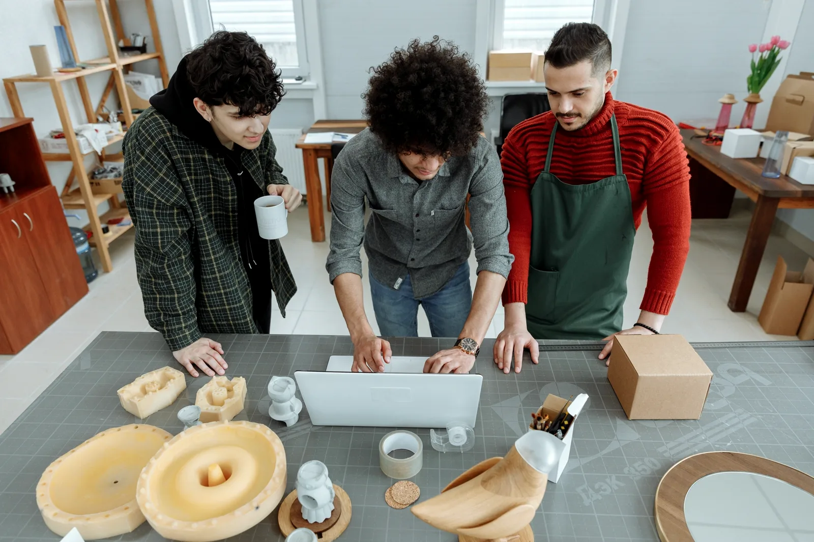 Three designers reviewing a product beside physical models in a workshop
