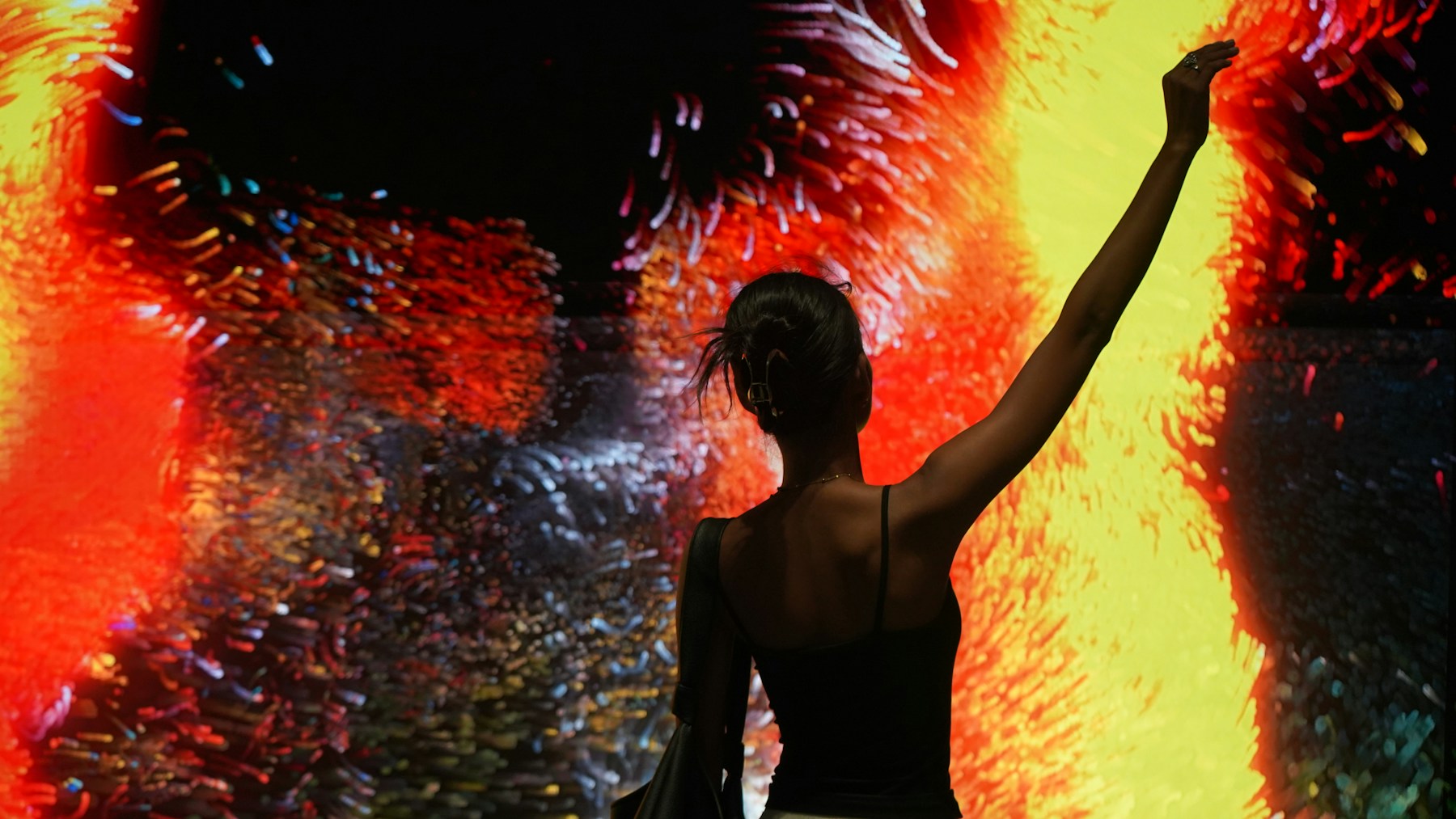 A person exploring a vivid projected art installation