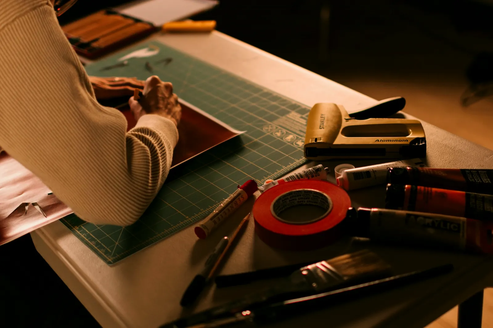 A designer working with a cutting mat, tools and materials on a workbench
